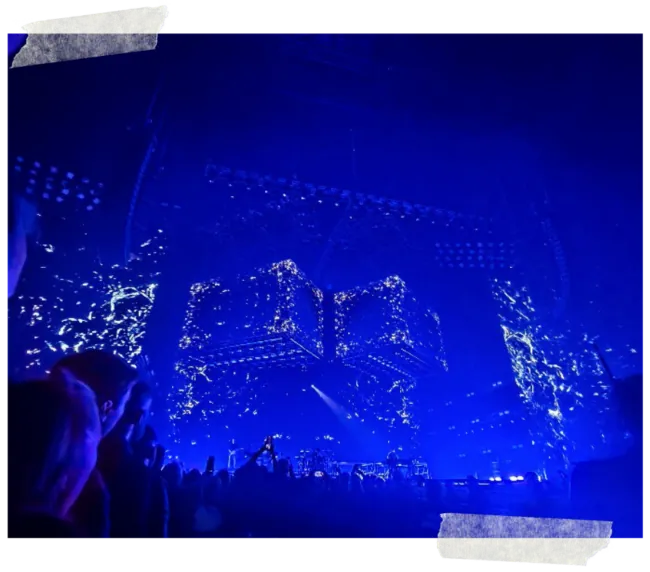 The arena seen from the floor, the lighting rig lit deep blue above the crowd