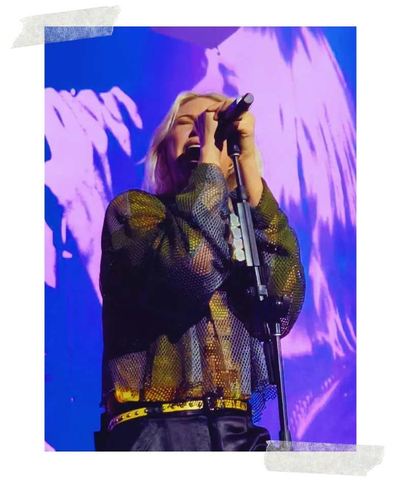 The singer at the microphone stand against a purple screen