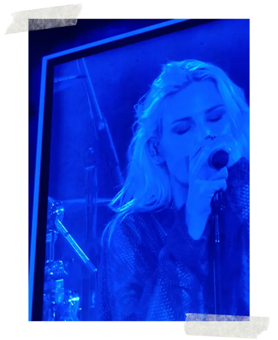 The stage screen carrying the singer in close-up, lit blue