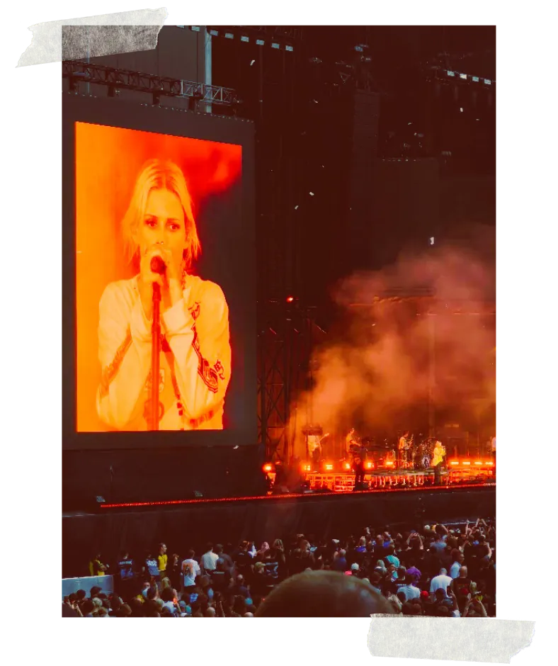 The stage screen carrying the singer in close-up, orange smoke rising over the stage