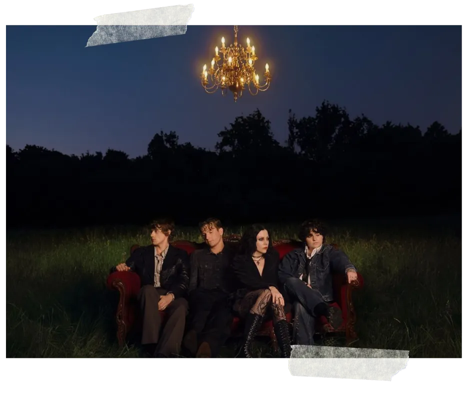 The four of them on a red velvet armchair in a dark field at dusk, a lit chandelier hanging above them