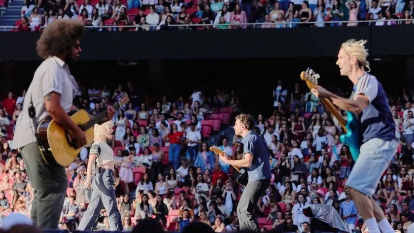 The band spread along the runway, the stadium stands packed behind them
