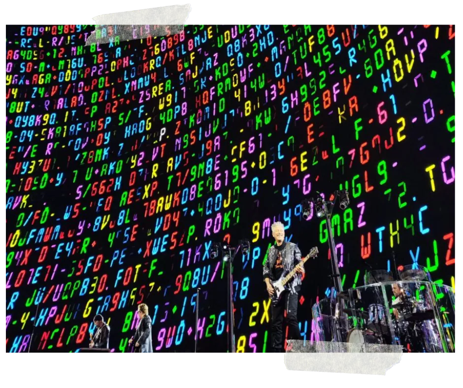 The band dwarfed by a wall of coloured characters and code filling the screen behind them