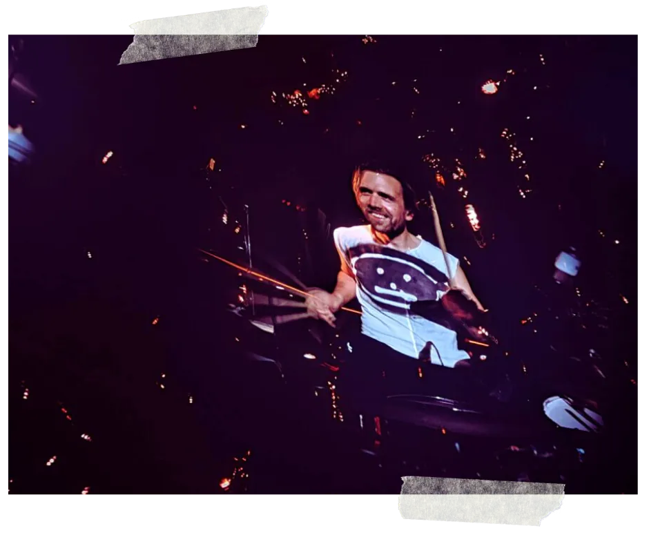The drummer in a smiley-face T-shirt carried on the screen above the stage